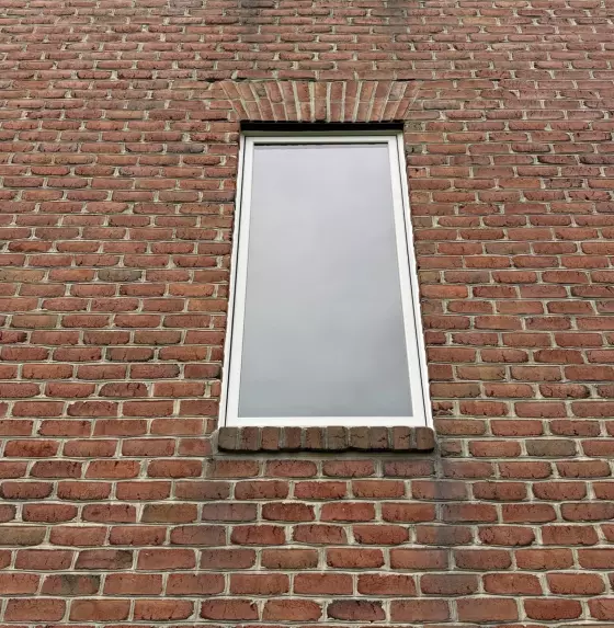 Brick exterior wall with two windows and white frames