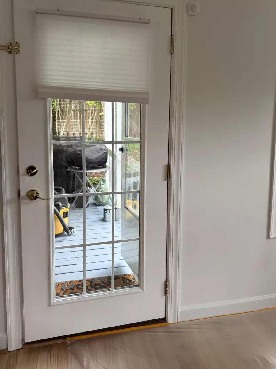 White glass door with gold handle and window blinds inside a home