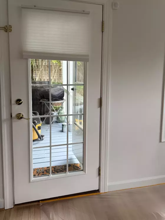 White glass door with gold handle and window blinds inside a home