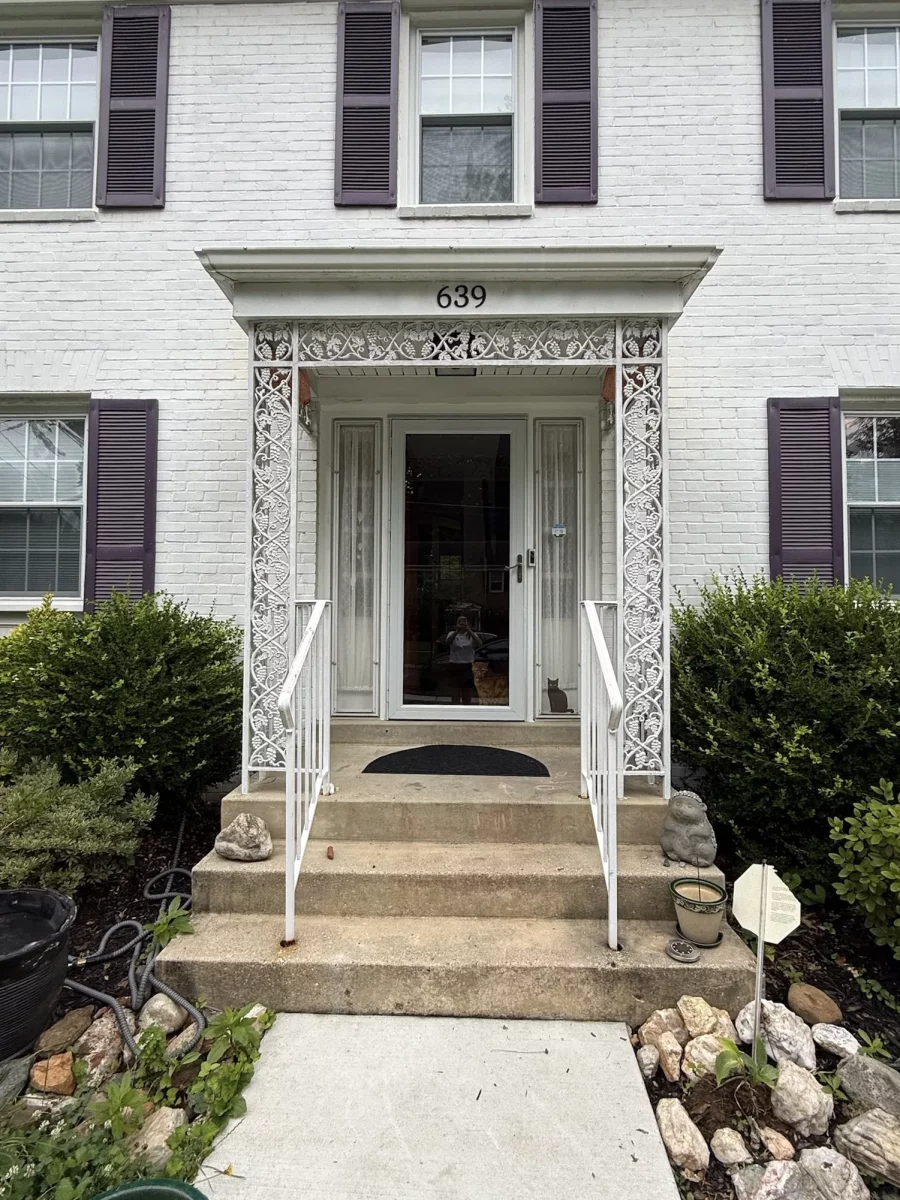 Front entrance of a residential building with steps, railing, and storm door