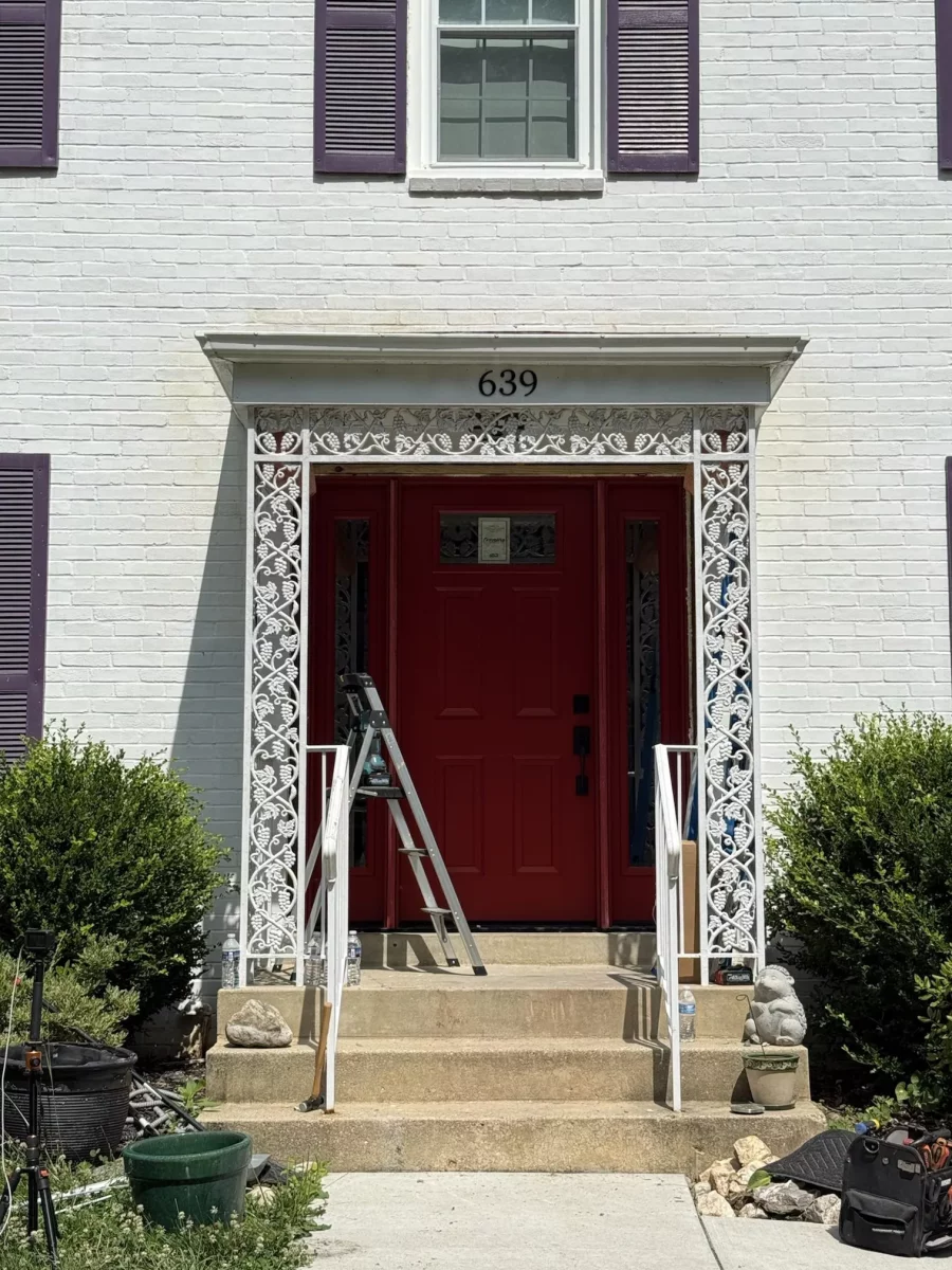New red ProVia entry door with sidelites installed under ornamental iron porch, exterior trim work in progress, Rockville