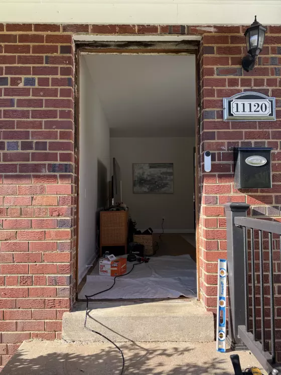 Brick house entry with door removed and tools visible