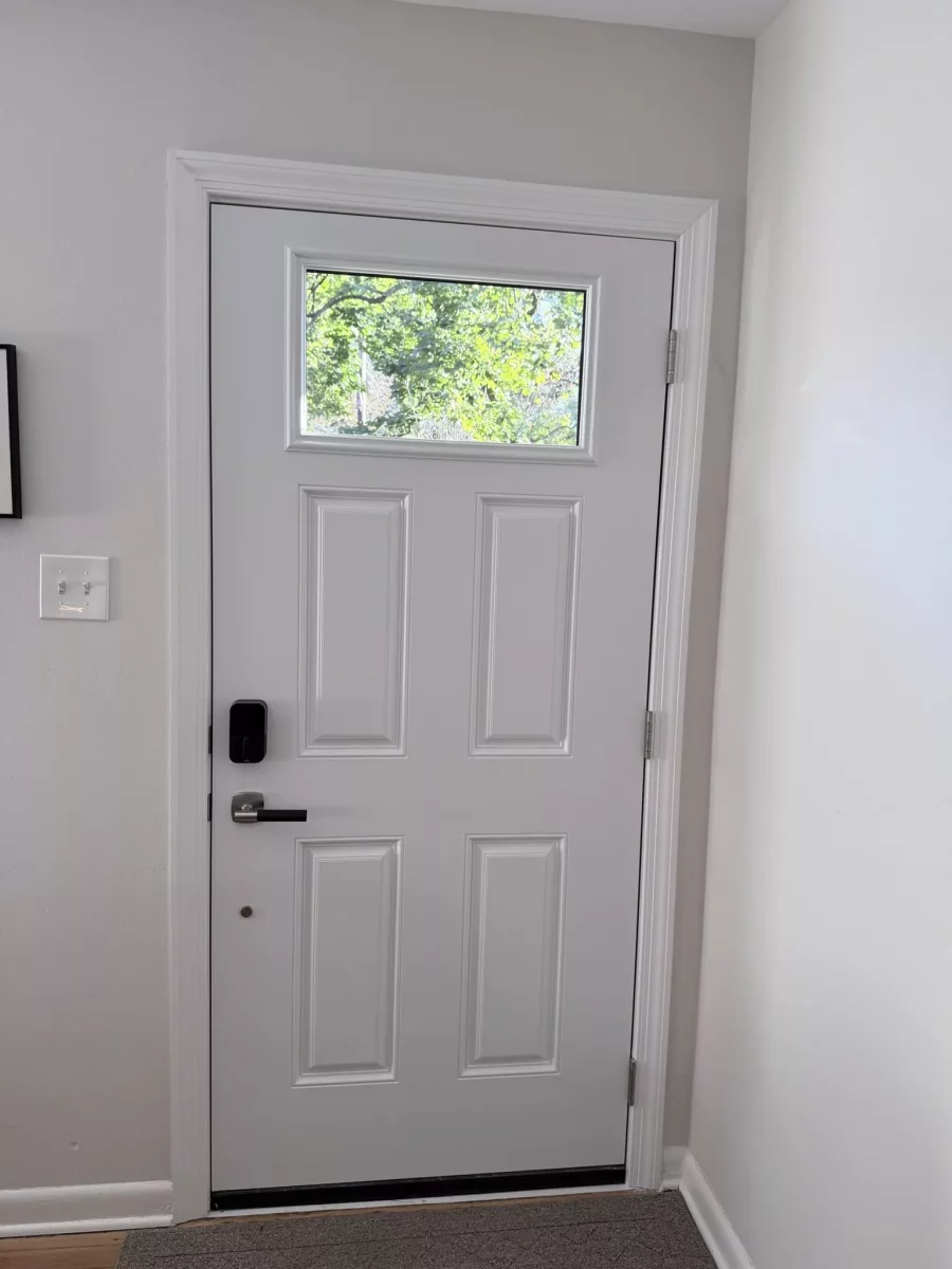 White entry door with window and black handle inside home