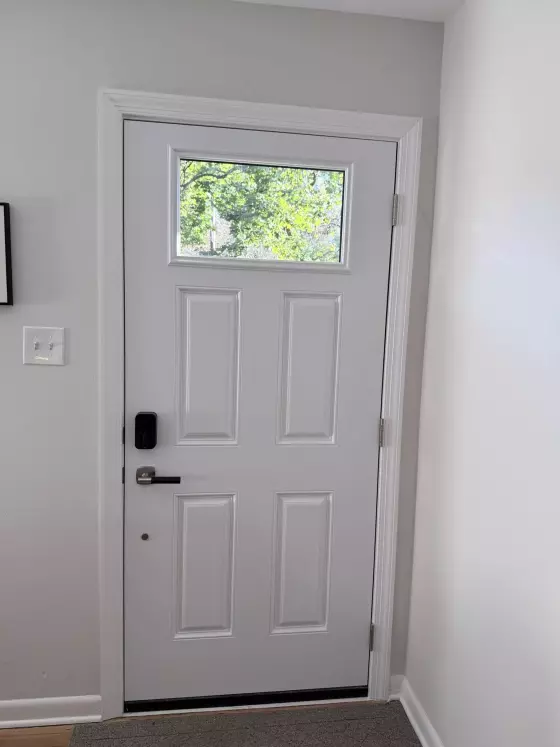 White entry door with window and black handle inside home