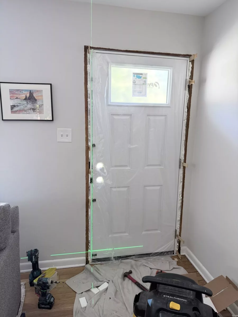 Entry door installation in progress with tools and protective film visible