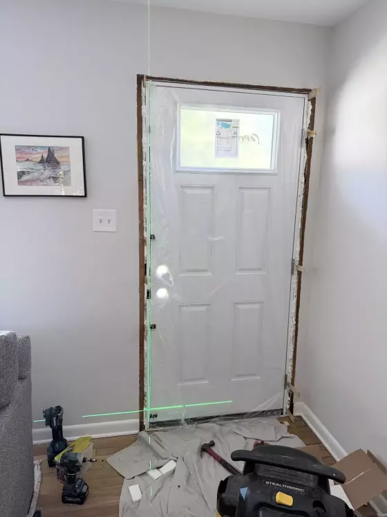 Entry door installation in progress with tools and protective film visible