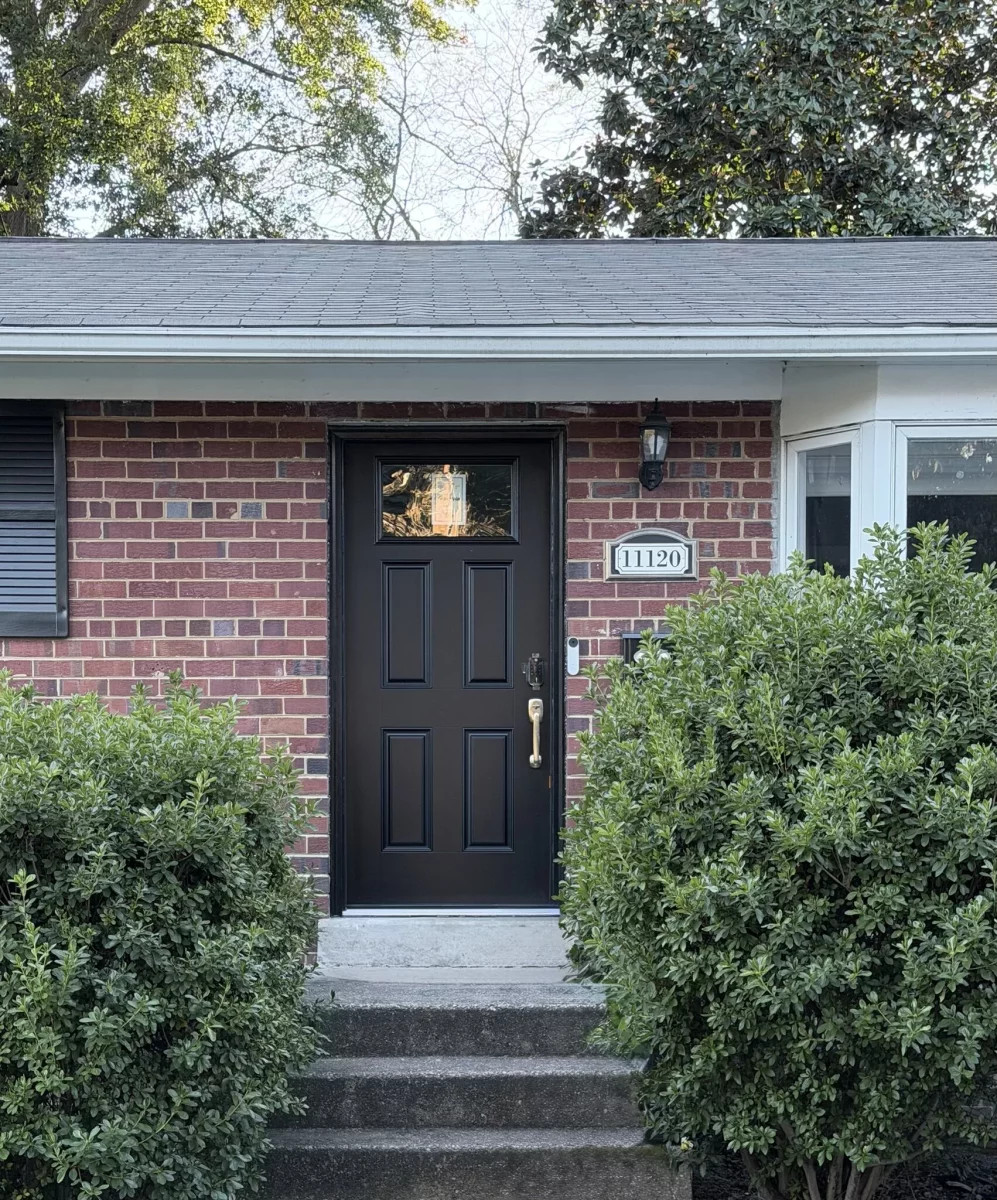 Black entry door installed on brick house exterior