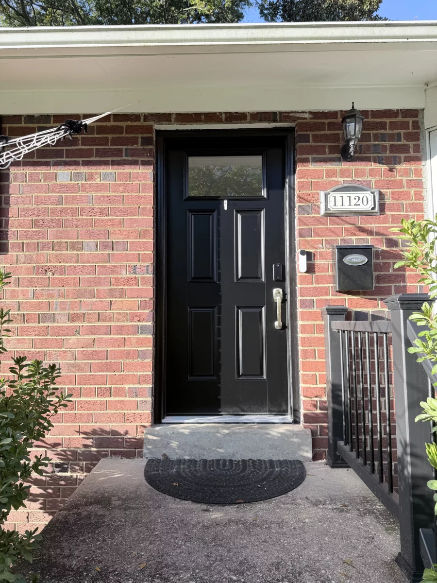 Black entry door installed on brick house exterior