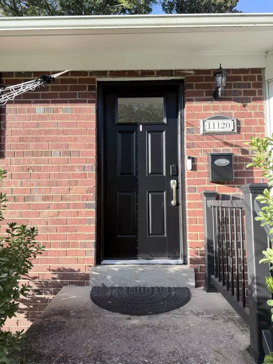 Black entry door installed on brick house exterior