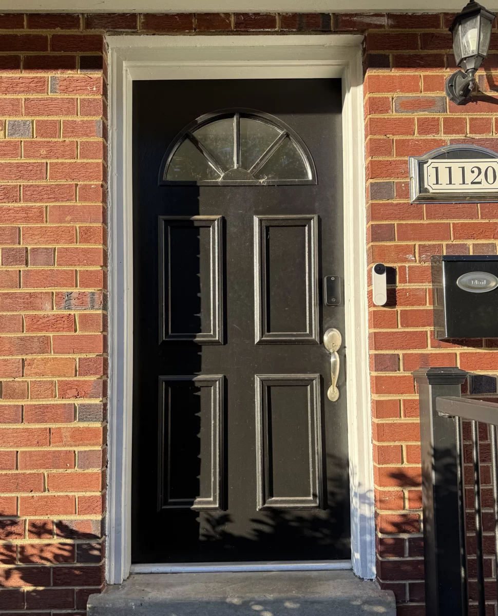 Black entry door with glass panel and brick exterior