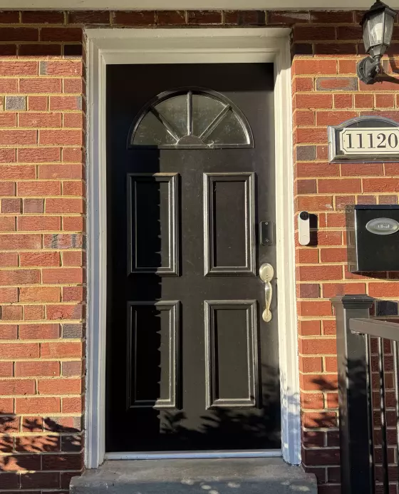 Black entry door with glass panel and brick exterior
