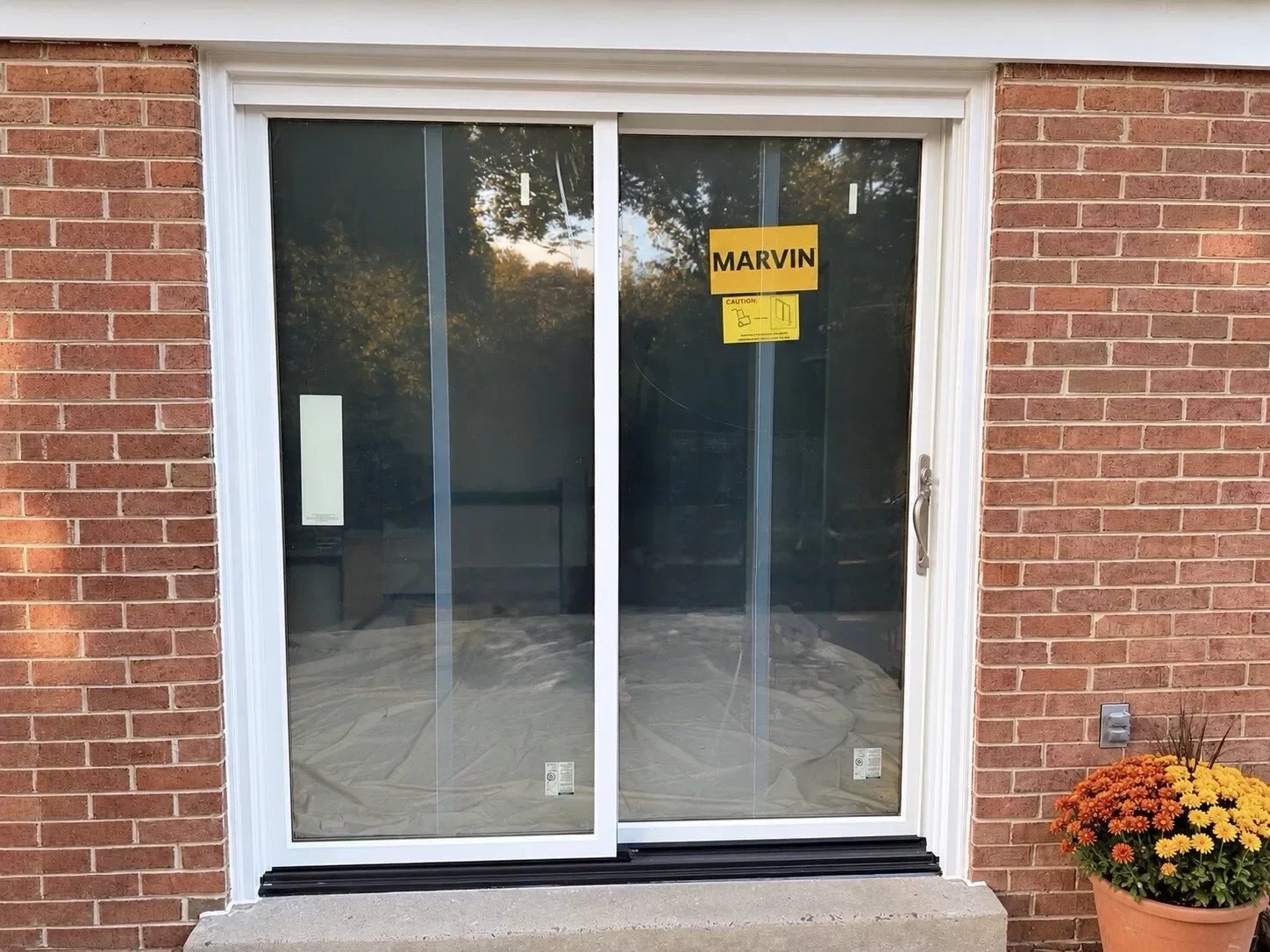 New white Marvin Elevate sliding patio door installed on a brick home in Glenwood, MD by All Dwelling Solutions