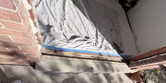 Door threshold area with brick wall, drop cloth, and power tool visible