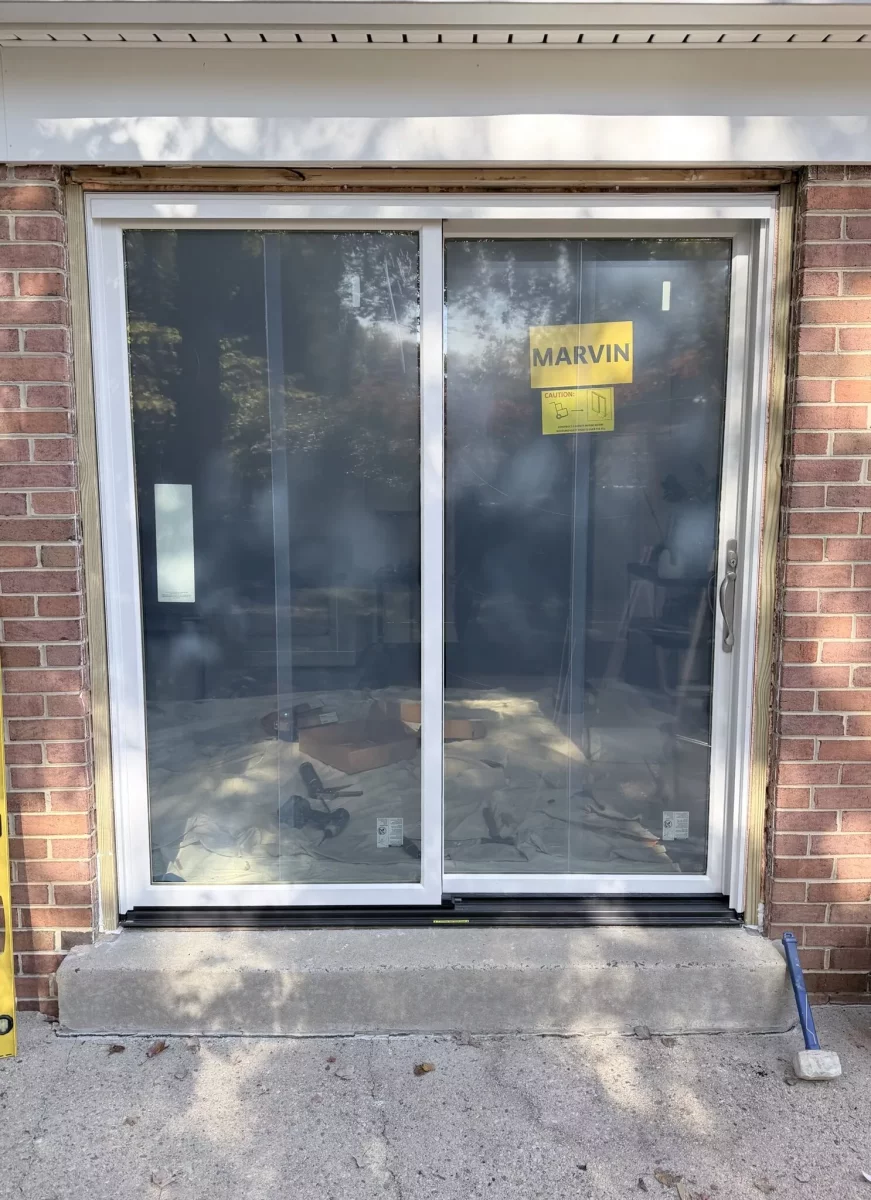 Sliding glass patio door being installed in brick exterior wall