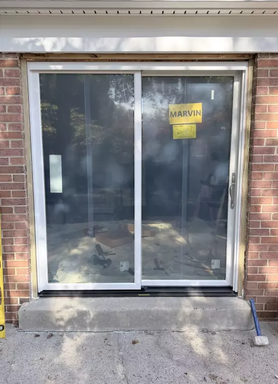 Sliding glass patio door being installed in brick exterior wall