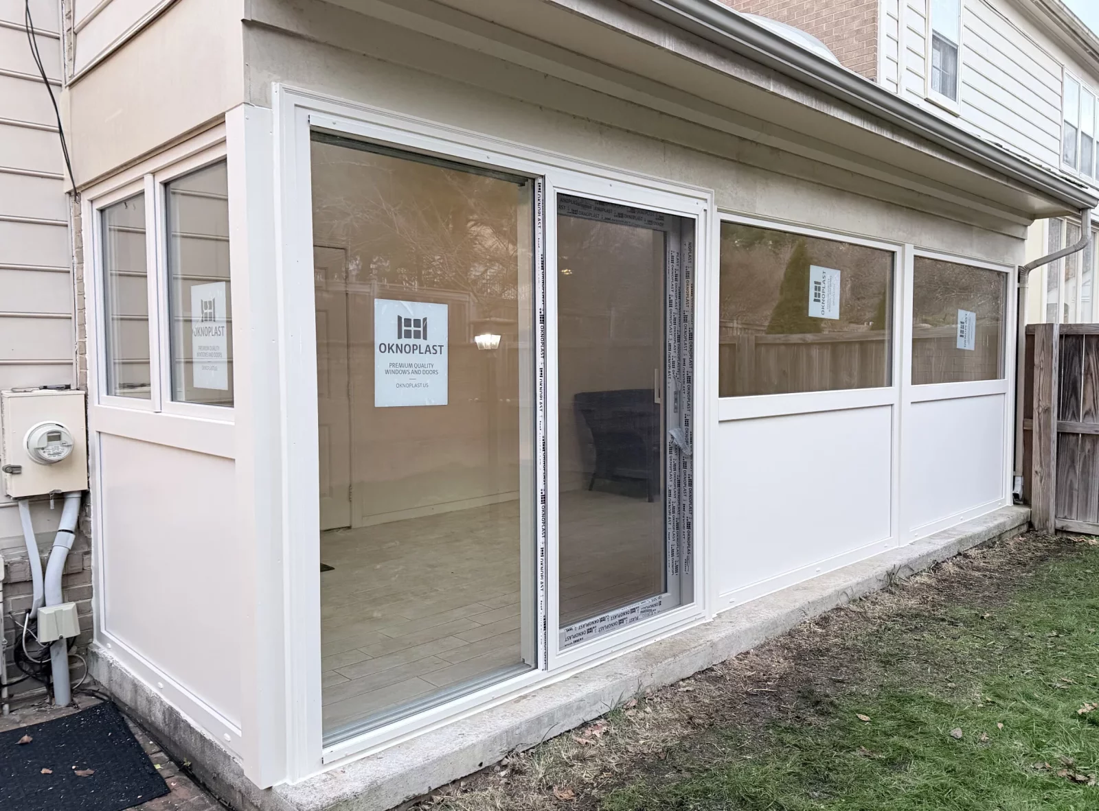 Exterior of enclosed sunroom with new cream Oknoplast windows, insulated panels, and sliding door in Potomac, MD