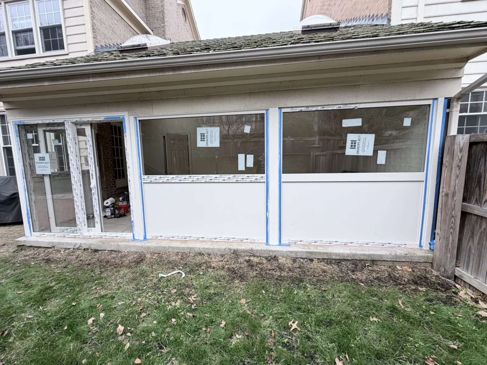 Oknoplast picture windows and sliding door being sealed and trimmed during sunroom enclosure in Potomac, MD