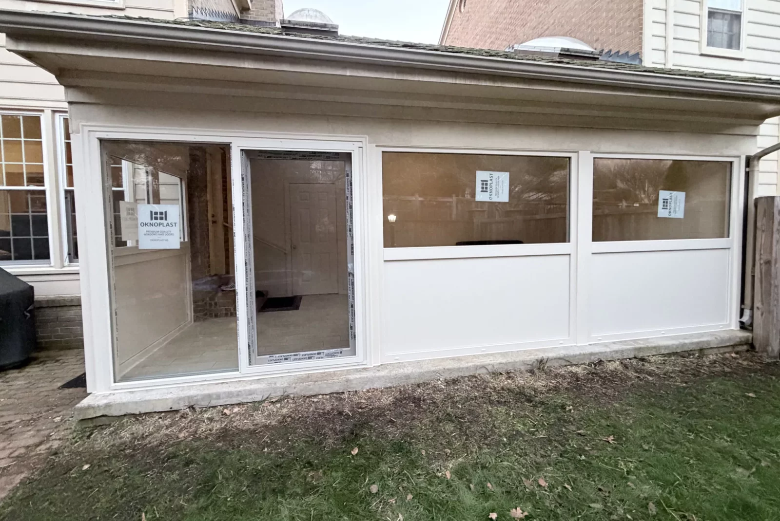 Exterior of enclosed sunroom with new cream Oknoplast windows, insulated panels, and sliding door in Potomac, MD