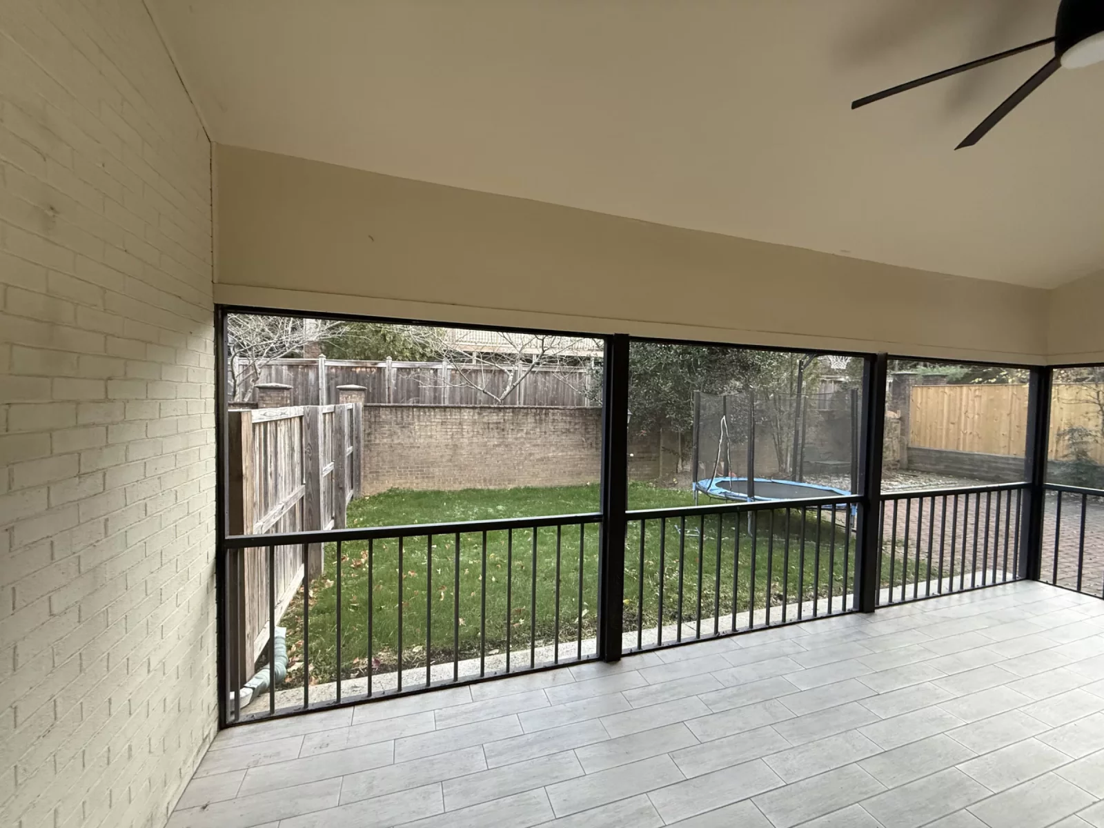 Screened patio with tiled floor and backyard view