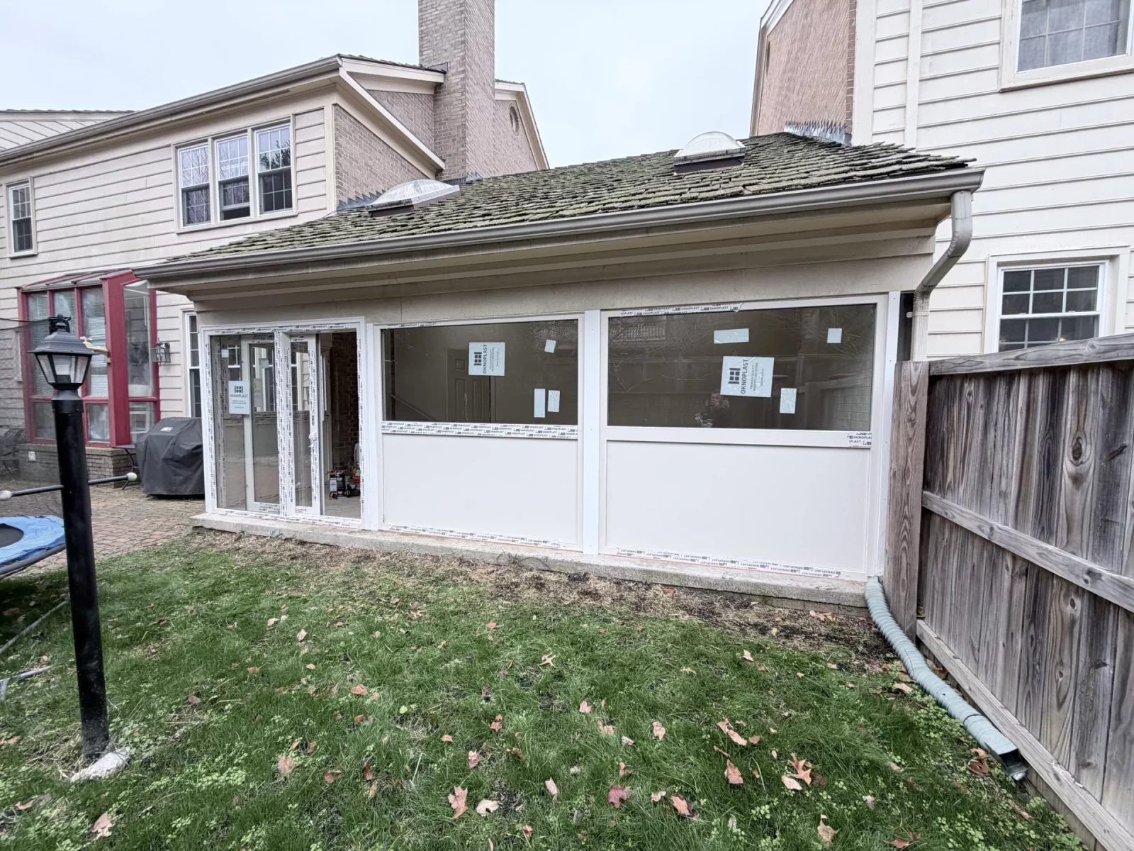 Exterior of enclosed sunroom with new cream Oknoplast windows, insulated panels, and sliding door in Potomac, MD