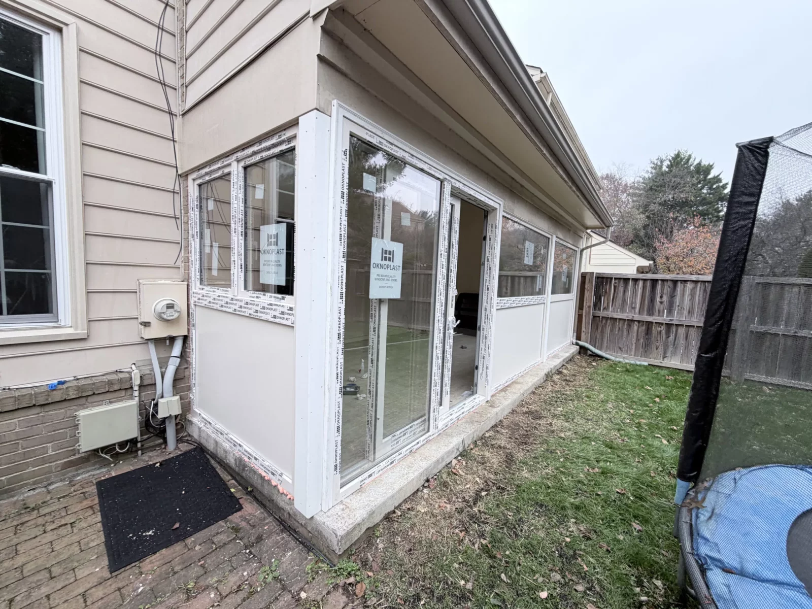 Exterior of enclosed sunroom with new cream Oknoplast windows, insulated panels, and sliding door in Potomac, MD