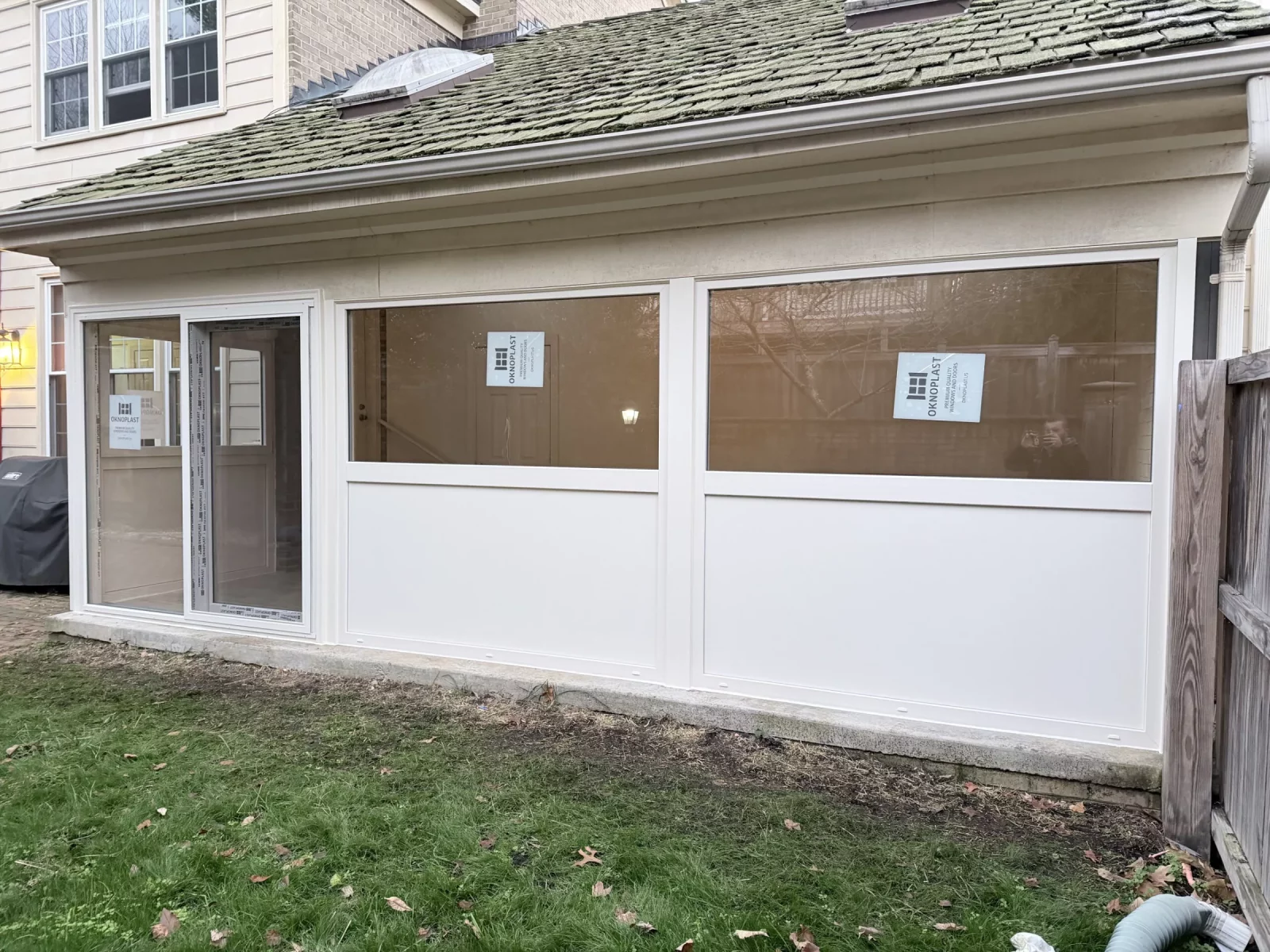 Exterior of enclosed sunroom with new cream Oknoplast windows, insulated panels, and sliding door in Potomac, MD
