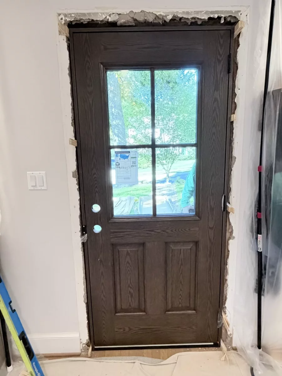 Entry door installation in progress with exposed frame and tools visible.