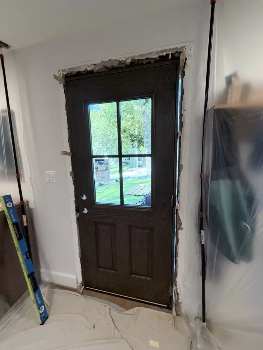 Entry door being installed with protective coverings and tools visible
