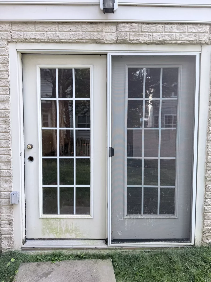Exterior view of a patio door with screen and brick wall