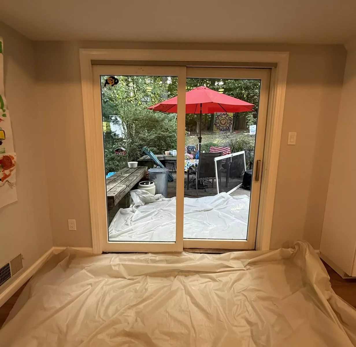 Old sliding patio door before replacement, interior view with floor protection in place in Silver Spring
