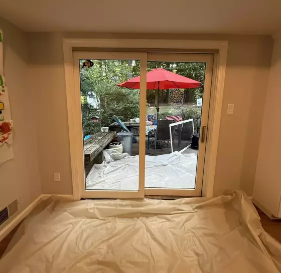 Old sliding patio door before replacement, interior view with floor protection in place in Silver Spring
