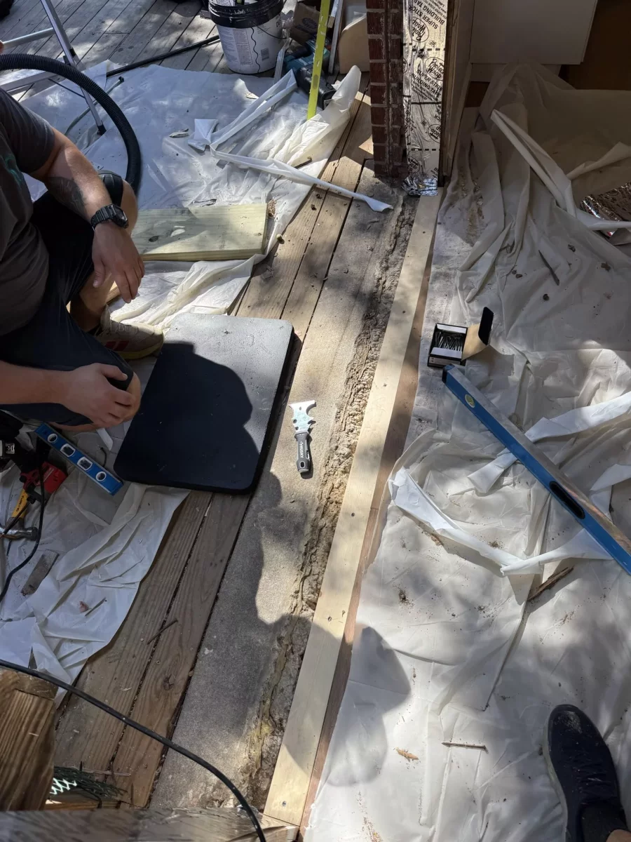 Installing new pressure-treated wood sill and flashing tape before sliding patio door replacement
