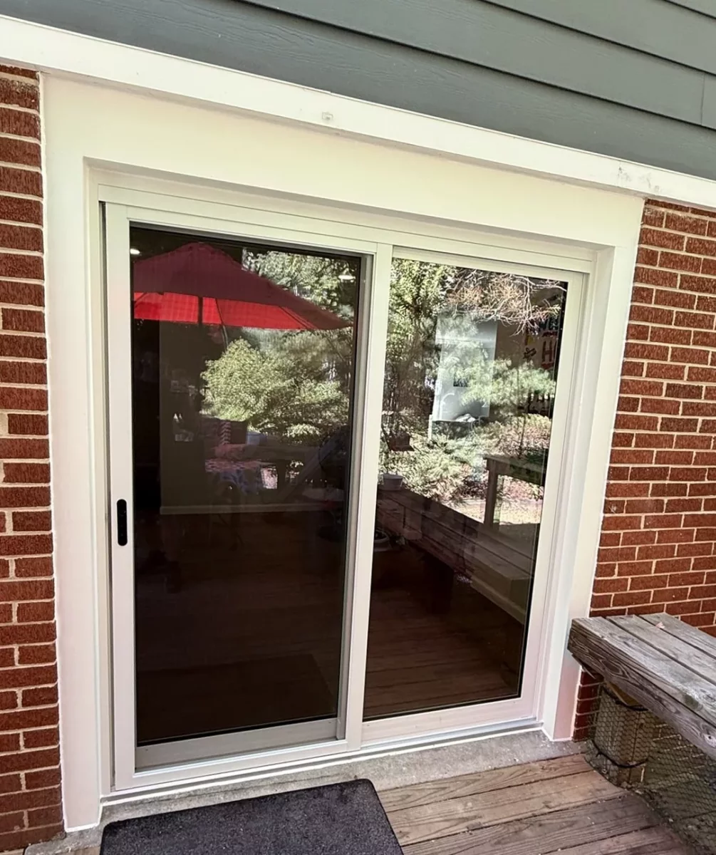 New white sliding patio door installed in brick wall with exterior trim, exterior view after replacement in Silver Spring, MD