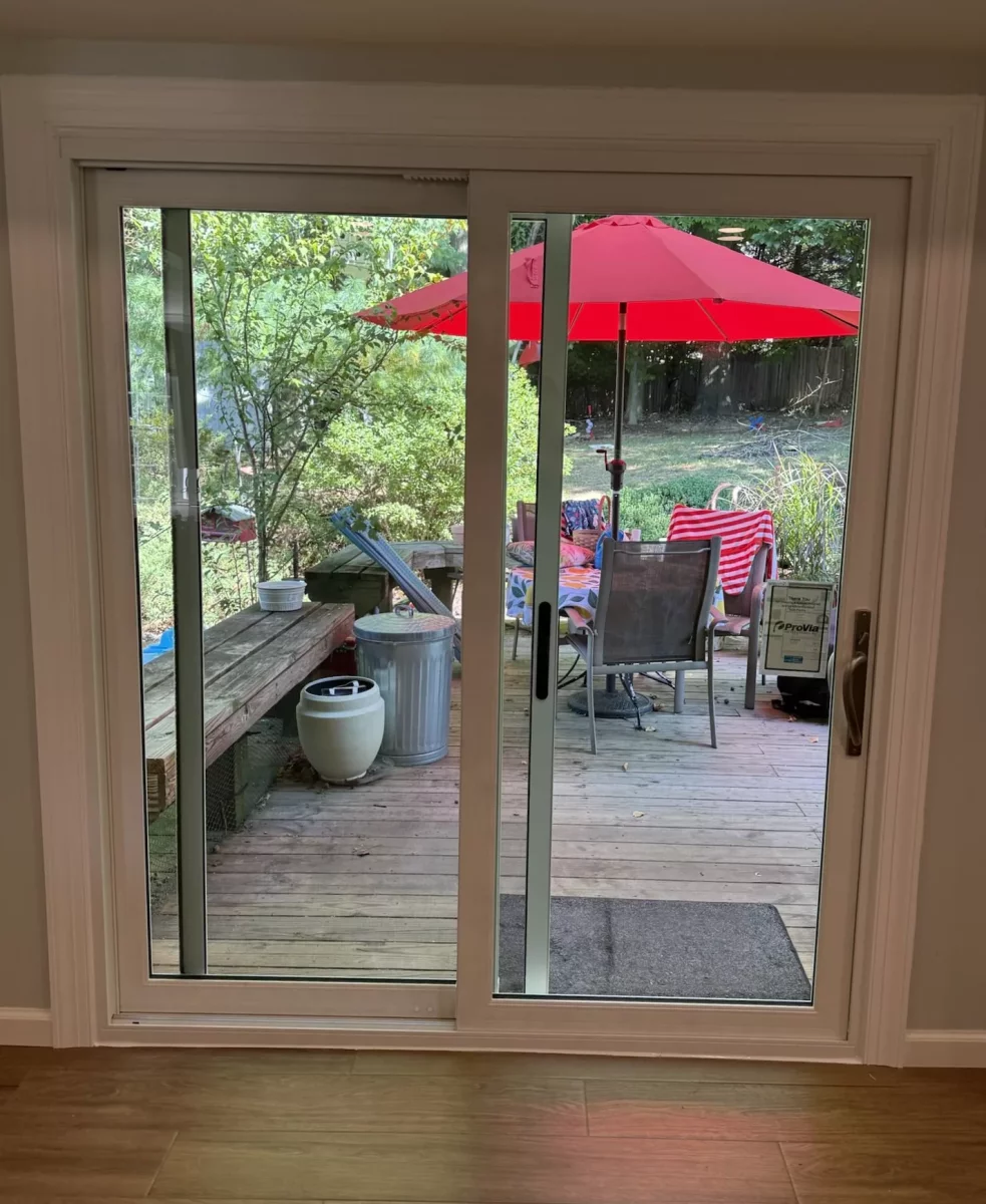 Sliding glass patio door with view to outdoor deck and red umbrella