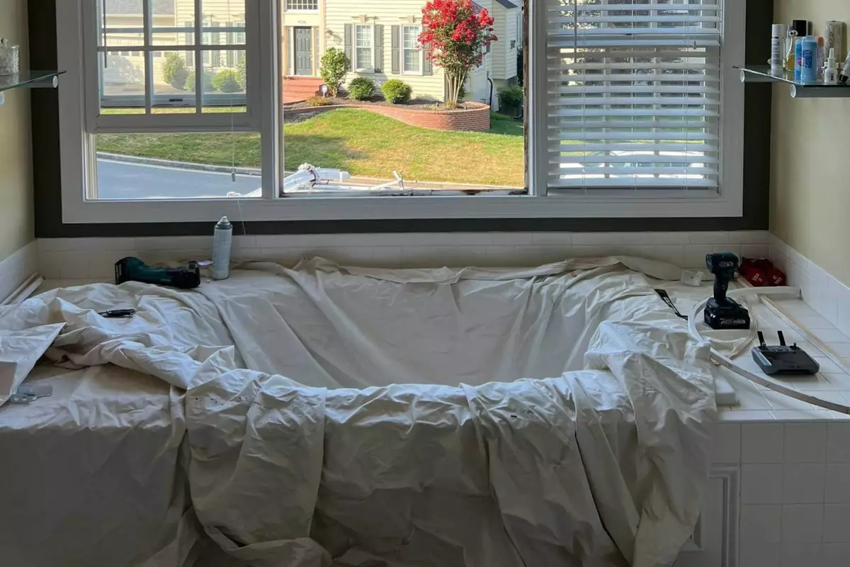 Window replacement in bathroom with protective coverings and professional tools showing careful preparation and respect for customer's home during service by All Dwelling Solutions